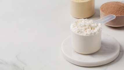 Various protein powders in scoops on gray background for fitness and nutrition. Copy space