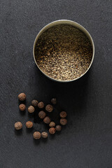 Black peppercorns and ground pepper on dark background