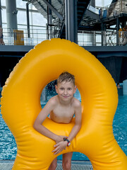 Teen boy with giant inflatable float in indoor water park