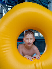 Teen boy with giant inflatable float in indoor water park