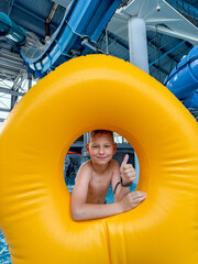 Teen boy with giant inflatable float in indoor water park