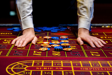 A player plays roulette in a casino. Close-up hand with chips on a roulette table. Gambling. Casino game concept.
