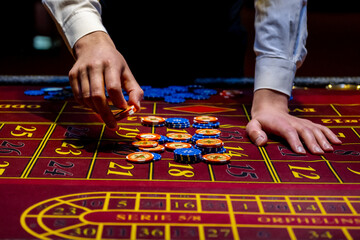 A player plays roulette in a casino. Close-up hand with chips on a roulette table. Gambling. Casino game concept.