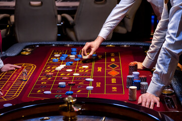 Croupier behind gambling table in a casino. Roulette wheel and croupier hand. A player in a casino,...