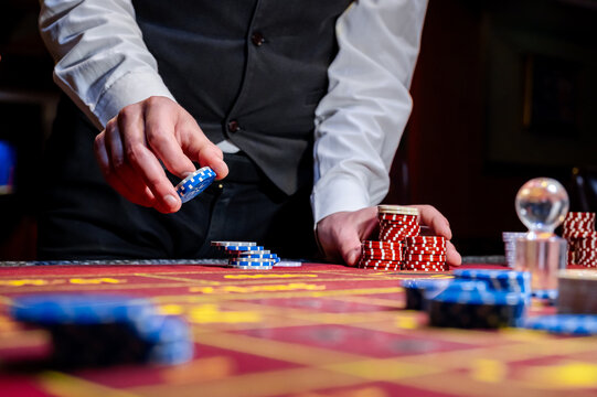 A man places a bet with chips in a casino. A player takes a lot of chips in a casino .Poker game in a casino in Las Vegas. Casino Black Jack table with poker cards