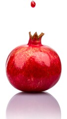 A pomegranate with a drop of juice falling