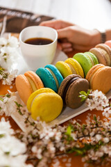 Many classic macaroons on white dishes, on an orange background in natural light