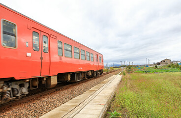 Fototapeta premium The vintage orange train going out from platform after boarding people for transportation, Japan.
