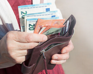 Leather wallet and euro banknotes in a woman's hands, selective focus.	
