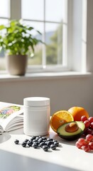 A white supplement jar sits on a bright white surface beside fresh fruits and blueberries, illuminated by natural light streaming through a nearby window.