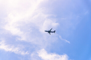 Airplane takes off into a blue sky with white clouds, Passenger plane aircraft flying across blue sky background, aircraft gaining altitude, view from below