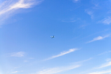 Airplane takes off into a blue sky with white clouds, Passenger plane aircraft flying across blue sky background, aircraft gaining altitude, view from below