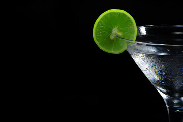 A glass of Ice water with lime closeup shot with copy space black background 