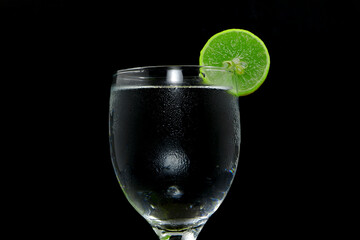 A glass of cool cooling water with lemon closeup shot on black background 