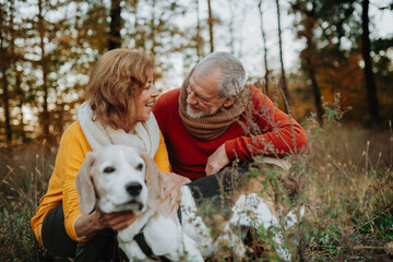 Senior couple walking dog in autumn forest.