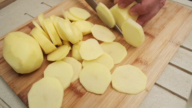 Precision slicing of potatoes on wooden board for culinary demonstrations.