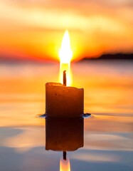 Candle floating on water at sunset