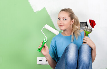 Young woman with paint tools in hands. Santa Claus Hat on brush. Christmas and New Year celebration
