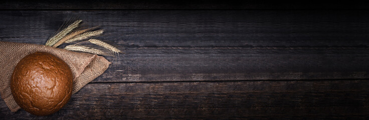 Fresh round bread on black wooden board, view with copyspace. Long banner