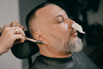 Caucasian male having relaxing barbershop treatment, ear and nose hair removal waxing