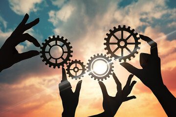 Hands of businessmen assemble a puzzle from gears against the sky in the sunset. business concept idea, partnership, innovation, teamwork, cooperation