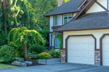 Garage door in luxury house with trees and nice landscape in Summer in Vancouver, Canada, North America. Day time on August 2025.