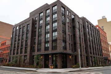 Obraz premium Modern brick building with large windows in urban setting features greenery and contemporary design near bustling street in city environment during overcast day