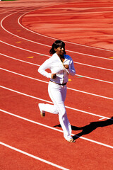 Young African American Woman Running On Track In White Outfit