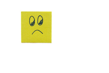 Sad face drawing on yellow sticky note