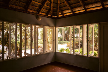 Bright and airy interior of a room with open windows and tropical vegetation outside