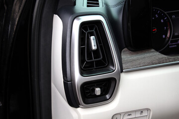 Naklejka premium Car interior air vent with silver surround, black fins, and metallic control knobs, set against beige and black dashboard with wood trim detail for a premium finish.