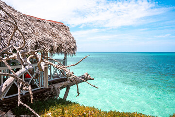 Tropical beach view with a straw hut overlooking the clear turquoise ocean