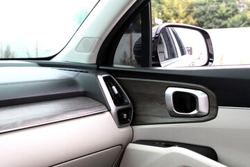 Modern car interior with beige and black trim, wood-style panel accents, air vent, door handle, and side mirror, combining sleek design and functional detailing. Lux premium white car interior.