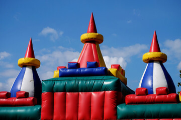 Colorful inflatable castle with pointed towers under a blue sky, designed for children's outdoor entertainment and fun activities