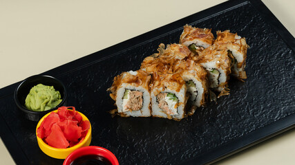 Sushi roll with soy sauce on black tray