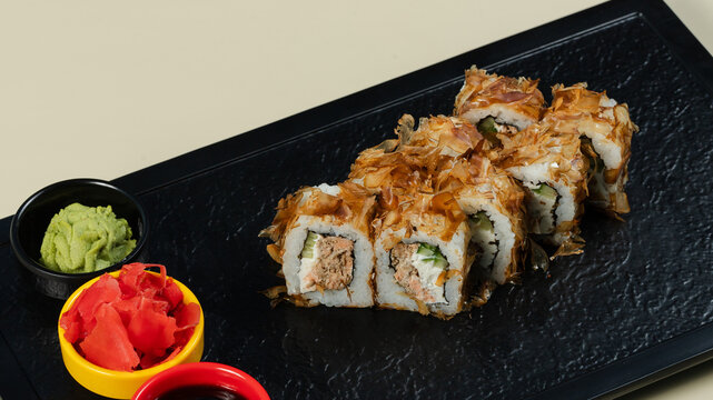 Sushi roll with soy sauce on black tray