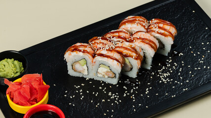 Sushi roll with soy sauce on black tray
