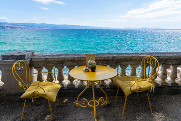 Cozy seaside cafe with yellow chairs, flowers, and stunning ocean view in opatia Croatia