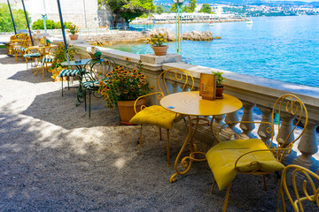Cozy seaside cafe with yellow chairs, flowers, and stunning ocean view in opatia Croatia