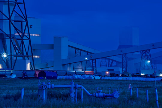 Industrial potash facility in Saskatchewan photographed at night with illuminated buildings and rail transport under a dark sky.
