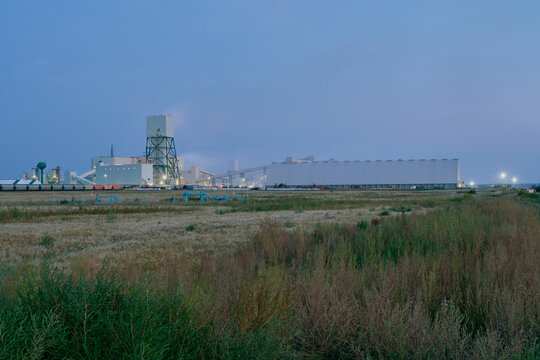 Industrial potash facility in Saskatchewan photographed at night with illuminated buildings and rail transport under a dark sky.
