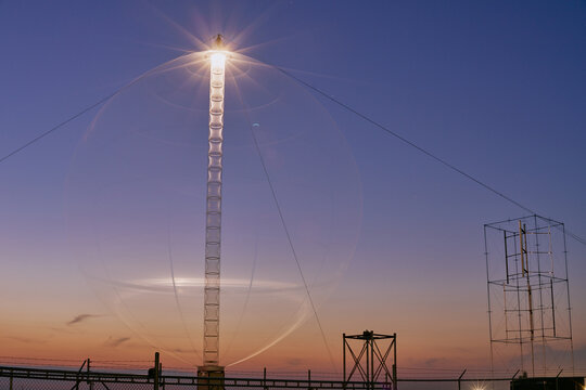 Illuminated vertical axis wind turbine tower in Saskatchewan photographed at night with bright lights against a dark sky.
