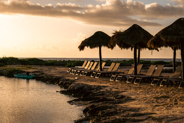 Beachside relaxing area with huts and sunbeds in a serene sunset ambiance.