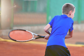 Young Boy tennis player In A Pose Of Hitting the tennis ball on court