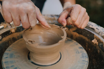 Clay molding on the wheel highlights pottery artistry and skill. Potter shaping clay bowl on a wheel. Clay spins gently under hands as potter forms bowl.