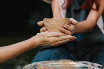Ceramic pot reflects artistry, patience, and cultural tradition. Finished clay pot in hands. Handmade clay bowl is held after removal from the wheel.
