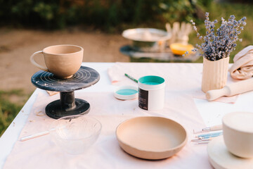 Artist carefully applies paint with a brush on clay bowl, showcasing the creative process of ceramic painting and the art of handcrafted pottery. Hand painting blue pain on ceramic bowl close-up.