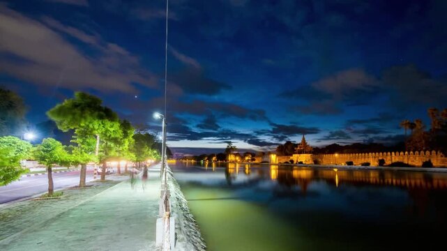 Mandalay palace glows along the moat at night in myanmar