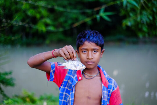 Boy holding a freshly caught fish, rural Bangladesh