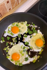 Scrambled eggs with freshly chopped green onions served on a plate, steaming hot and ready to eat.